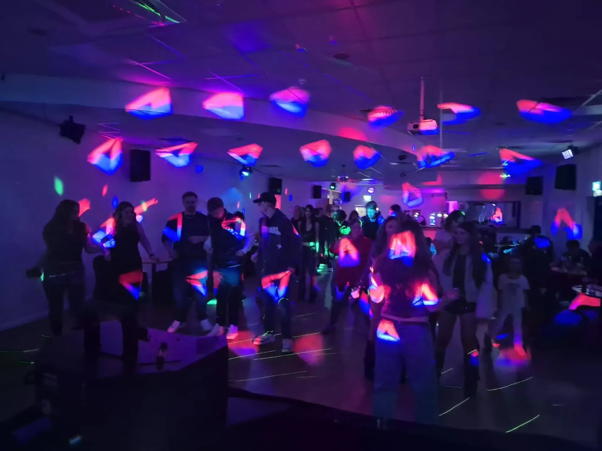 Party guests dancing under coloured DJ lighting