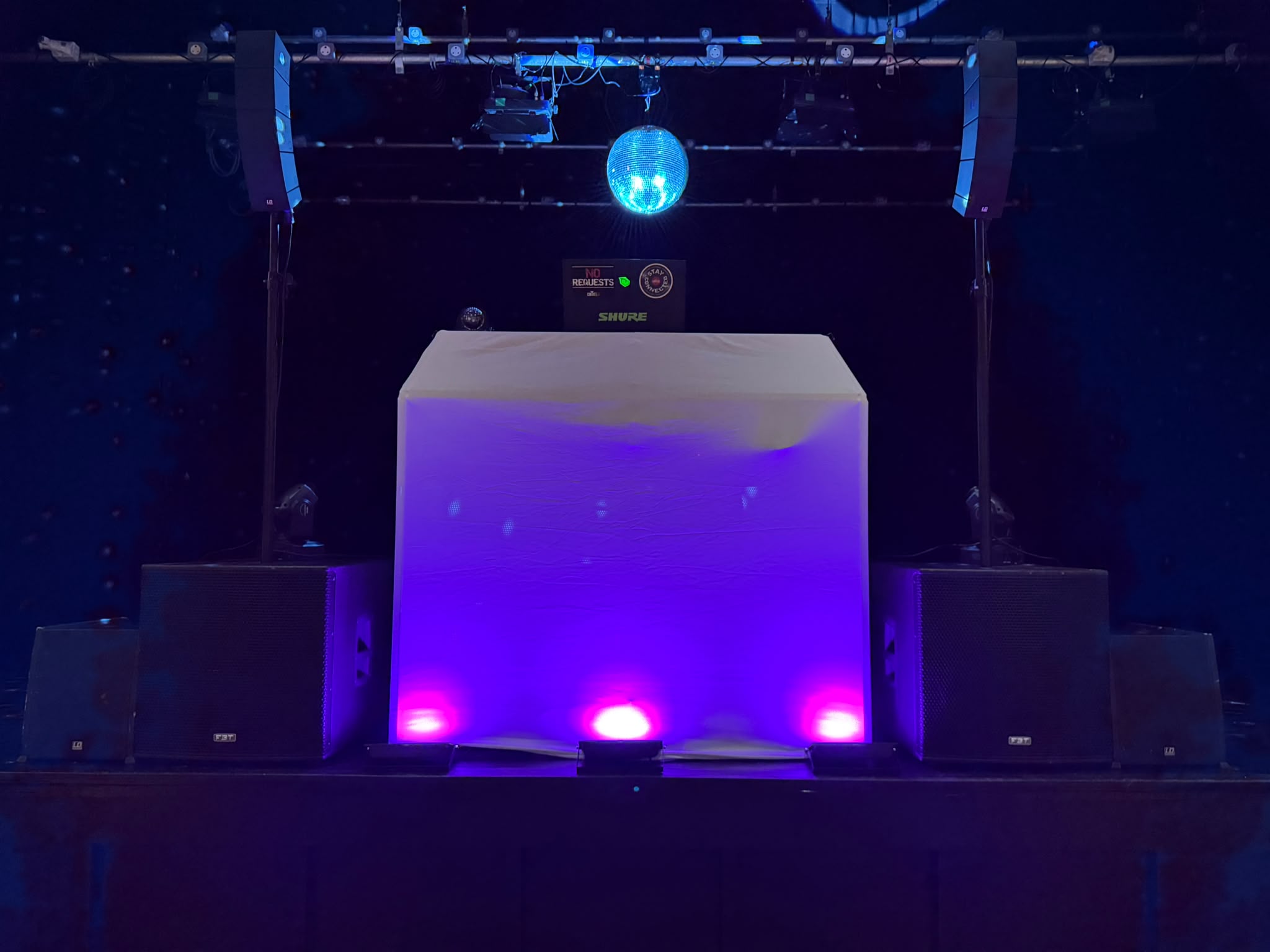 DJ booth with line array speakers and mirror ball on stage